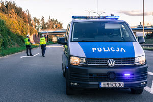 Widoczni umunudrowani policjanci i radiowozy oraz kibice w drodze na mecz