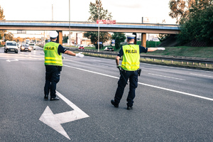 Widoczni umunudrowani policjanci i radiowozy oraz kibice w drodze na mecz