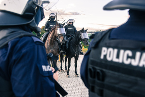 Widoczni umunudrowani policjanci i radiowozy oraz kibice w drodze na mecz