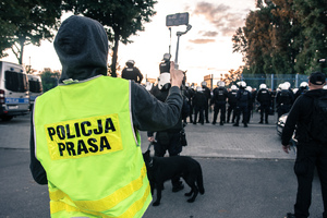 Widoczni umunudrowani policjanci i radiowozy oraz kibice w drodze na mecz