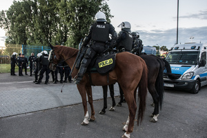 Widoczni umunudrowani policjanci i radiowozy oraz kibice w drodze na mecz