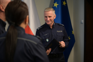 Na zdjęciu policjant na tle polskiej flagi.