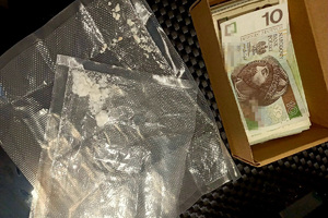 zdjęcie przedstawia zabezpieczony biały proszek oraz zabezpieczone banknoty