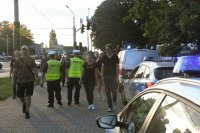 Policjanci ruchu drogowego w rejonie skrzyżowania, widoczni piesi, radiowozy oraz samochody,