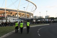 Trzy policjantki w trakcie patrolu pieszego, w tle uczestnicy koncertu oraz Stadion Śląski