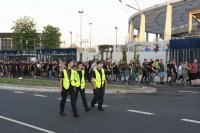 Trzy policjantki w trakcie patrolu pieszego, w tle uczestnicy koncertu oraz Stadion Śląski