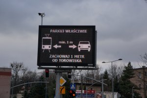 Tablica systemu ITS z wyświetlanym komunikatem :Parkuj właściwie, zachowaj jeden metr od torowiska&quot;