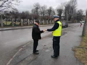 policjant wręczający przechodniowi odblaski