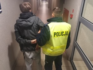 Zdjęcie przedstawia zatrzymanego, oraz prowadzącego go policjanta