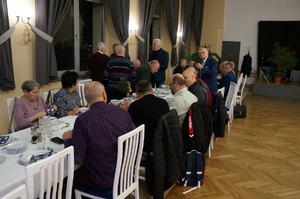 Zdjęcie przedstawia uczestników spotkania wigilijnego w trakcie składania życzeń.