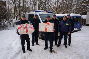 Zdjęcie przedstawia policjantów oraz strażników miejskich trzymających prezenty.