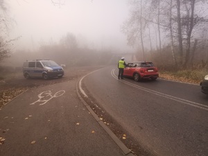 Zdjęcie przedstawia policjanta badającego trzeźwość kierującego oraz policyjny radiowóz.