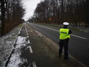 Zdjęcie przedstawia policjanta podczas pomiaru prędkości