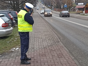 Zdjęcie przedstawia policjanta podczas pomiaru prędkości