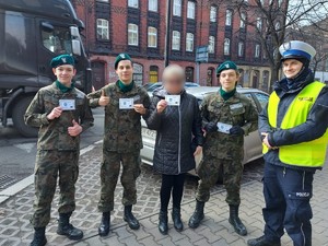 Zdjęcie przedstawia policjantów oraz uczniów podczas wręczania mandatów zaufania