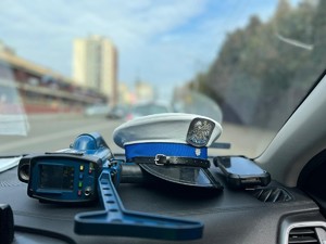 Zdjęcie przedstawia policyjną czapkę i miernik prędkości wewnątrz radiowozu