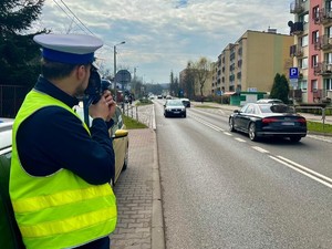 Zdjęcie przedstawia policjanta podczas pomiaru prędkości