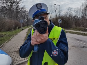 Zdjęcie przedstawia policjanta podczas pomiaru prędkości