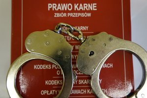 Zdjęcie przedstawia Kodeks Karny oraz kajdanki