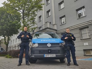 Zdjęcie przedstawia policjantów obok radiowozu