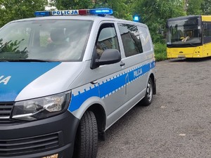 Zdjęcie przedstawia policyjny radiowóz, w tle kontrolowany autobus.
