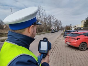 Zdjęcie przedstawia policjanta podczas pomiaru prędkości