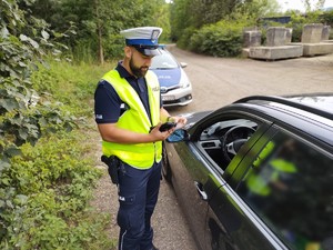 Zdjęcie przedstawia policjanta podczas kontroli drogowej