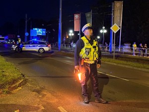 Zdjęcie przedstawia policjanta kierującego ruchem trzymającego w ręku latarkę