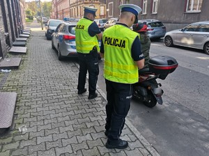 Zdjęcie przedstawia dwóch policjantów podczas kontroli motorowerzystki