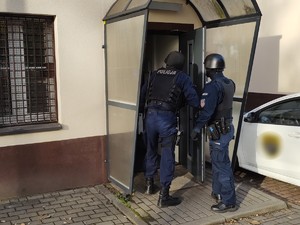 Zdjęcie przedstawia policjantów wyposażonych w hełmy i długa broń wchodzących na teren WCR