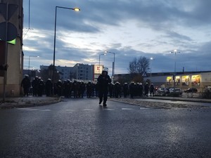 Zdjęcie przedstawia policjantów prowadzących przemarsz kibiców