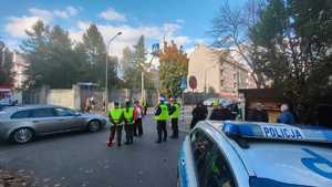 Zdjęcie przedstawia uczniów oraz policjantów przy jednym z cmentarzy