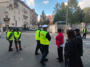 Zdjęcie przedstawia policjantów oraz młodzież z II L.O. w rejonie cmentarza