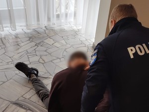 Zdjęcie przedstawia zatrzymanego mężczyznę oraz policjanta