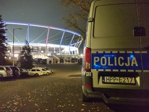 Zdjęcie przedstawia policyjny radiowóz na tle Stadionu Śląskiego