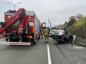 Zdjęcie przedstawia osobówkę biorącą udział w kolizji oraz pojazd straży pożarnej i radiowóz