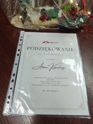 Zdjęcie przedstawia podziękowanie za współpracę dla Pana Adama Kościelnego. Poniżej cytat św. Jana Pawła II: „Człowiek jest wielki nie przez to co posiada, lecz przez to kim jest, nie przez to co ma, lecz przez to czym się dzieli z innymi”