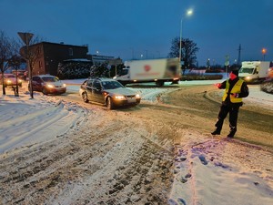 Zdjęcie przedstawia policjanta zatrzymującego pojazd do kontroli