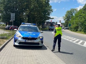 Zdjęcie przedstawia policjantę zatrzymującą samochód do kontroli