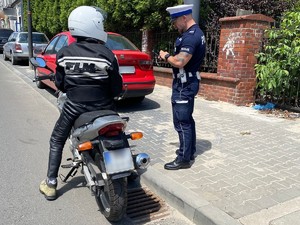 Zdjęcie przedstawia kontrolę motocyklisty przez policjanta drogówki