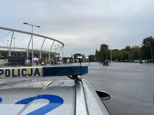 Zdjęcie przedstawia policyjny radiowóz na tle stadionu