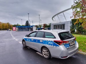 Zdjęcie przedstawia policyjny radiowóz na tle stadionu