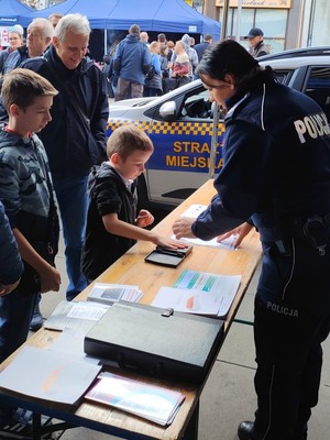 Zdjęcie przedstawia policjantkę oraz dziecko w trakcie wykonywania daktyloskopii