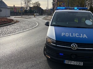 Na zdjęciu policyjny radiowóz oraz policjant zabezpieczający trasę biegu.