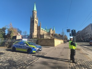 Na zdjęciu policjant oraz radiowóz w rejonie chorzowskiego cmentarza