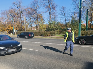 Na zdjęciu policjant drogówki zatrzymujący samochód do kontroli drogowej