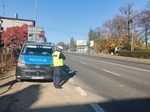 Na zdjęciu radiowóz oraz policjant ruchu drogowego wykonujący pomiar prędkości