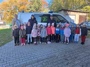 Grupowe zdjęcie przedszkolaków i policjantów na tle radiowozu.