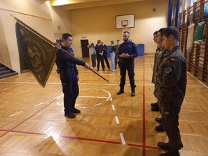 Na zdjęciu dwójka policjantów ze sztandarem i uczniowie szkoły.