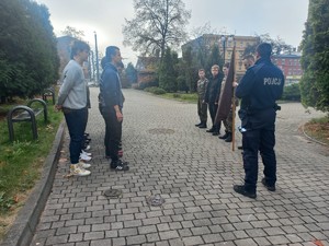 Zdjęcie na zewnątrz szkoły. Dwójka policjantów i uczniowie szkoły.